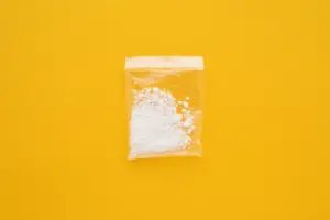 Cocaine drug in resealable bag on bright yellow background