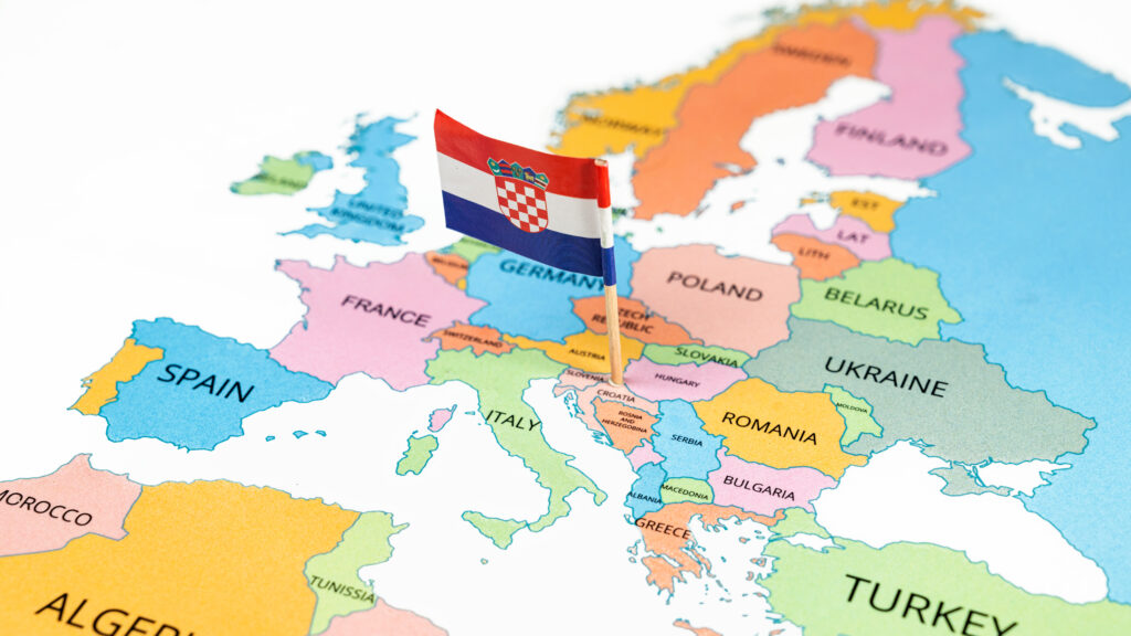 A map of Croatia with the national flag of Croatia on it. The flag is a horizontally striped red-white-blue national flag with the national coat of arms in its center. Travel and government concept
